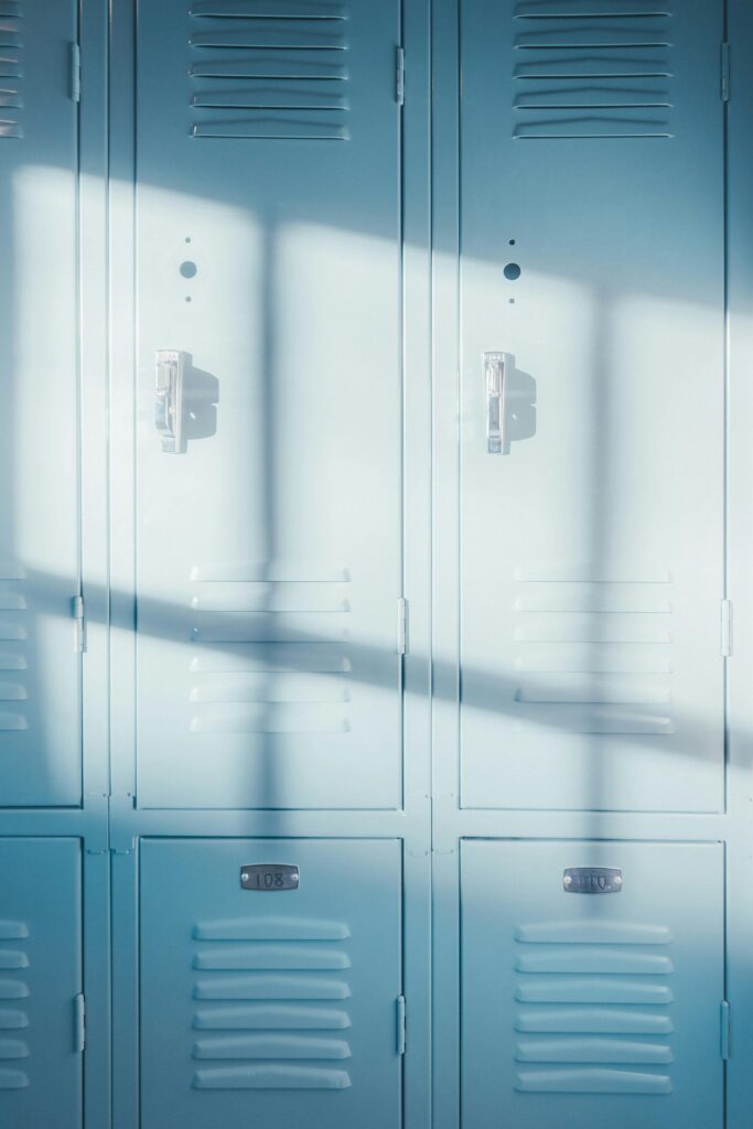 A row of bright blue school lockers illuminated by natural sunlight, casting shadows.